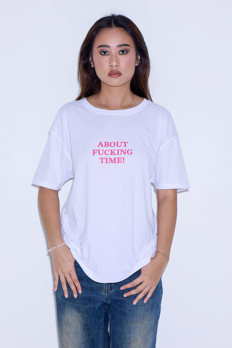 Person wearing a white t-shirt with pink text on a plain background