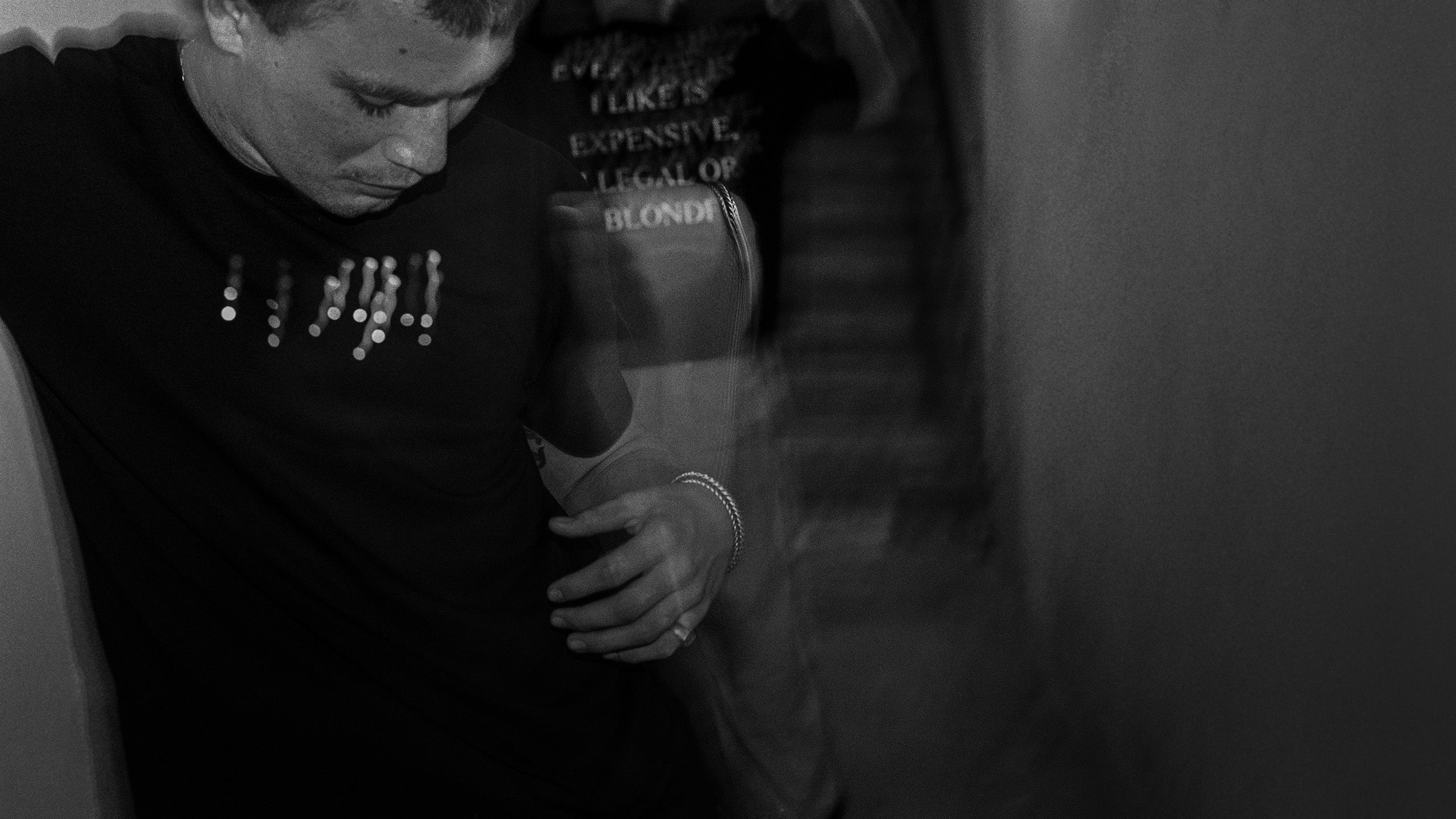 Model wearing black Z&T Braille shirt from Carpe Noche collection with Vice shirt in the background photographed at night with flash photograpy